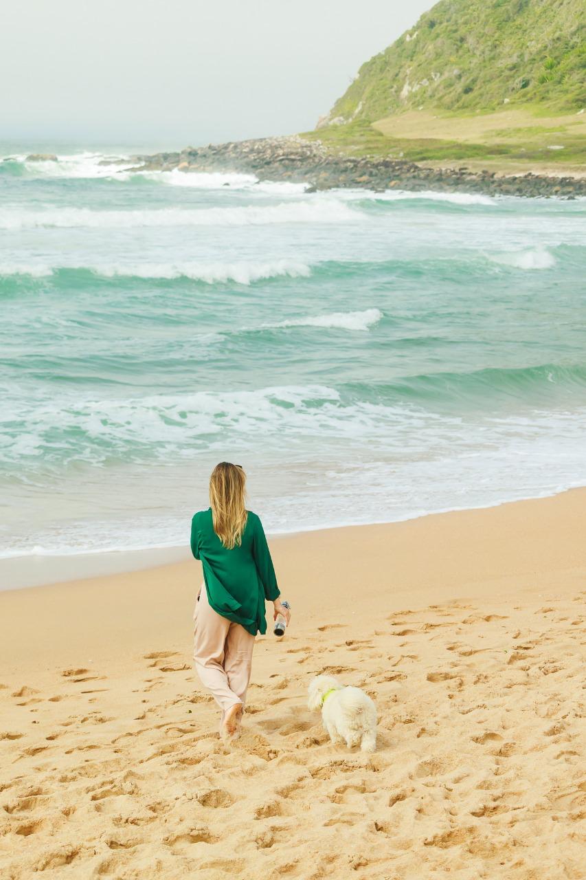 Mariana Schneider caminhando na praia com o Simba